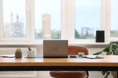 Modern dizüstü bilgisayarı ve ahşap masa üzerindeki kırtasiyesi olan şık bir iş yeri.