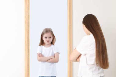 Genç bir kadın kendini aynada çocuk olarak görüyor. Geçmiş ve gelecek hakkında kavramsal kolaj, zaman akışı, yaş