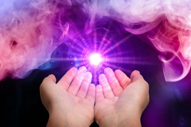 Siyah arka planda parlak bir ışık yaratan kadın, yakın plan. Aura, ruhani uygulama.