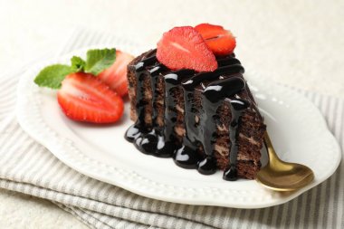 Bir parça çikolatalı kek, beyaz masada çilekli, yakın plan.