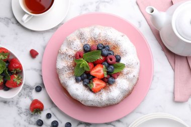 Beyaz mermer masada pudra şekeri ve böğürtlenli Lezzetli Bundt keki.