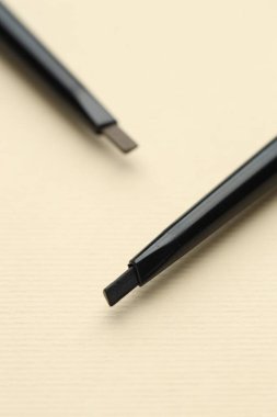 Bej arka planda otomatik kaş kalemleri, makro görünüm