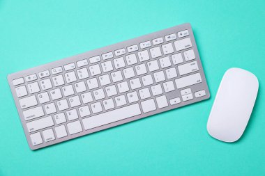 Turkuaz arka planda modern kablosuz bilgisayar klavyesi ve fare düz konum