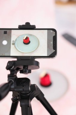 Stüdyoda akıllı telefonla lezzetli bir tatlı çekmek, seçici bir odak noktası. Profesyonel yemek fotoğrafçılığı.