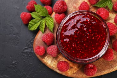 Cam kavanozda tatlı ahududu reçeli ve gri desenli masada böğürtlen.