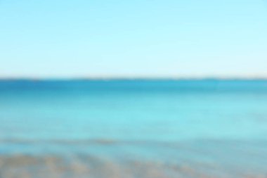 Açık mavi gökyüzünün altında güzel bir deniz, bulanık bir manzara.