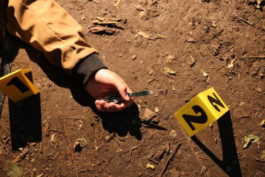 Adli tıp uzmanlığı. Cesedin olduğu suç mahalli, bıçak ve işaret açık havada, üst tarafta.