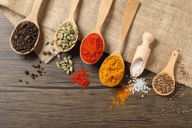 Farklı aromatik baharatlar kaşıklarda ve kepçeyle tahta masada, düz yerde
