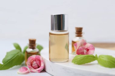 Beyaz masada kozmetik ürünleri, güller ve fesleğenler, yakın plan.