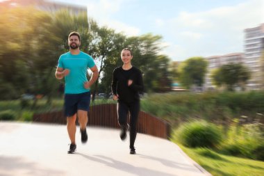 Spor giyimli kadın ve erkek açık havada koşuyor, hareket bulanıklığı etkisi