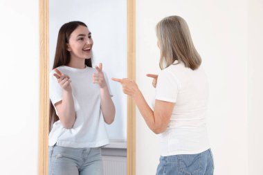 Kıdemli kadın kendini aynada genç bir kız olarak görüyor. Geçmiş ve gelecek hakkında kavramsal kolaj, zaman akışı, yaş