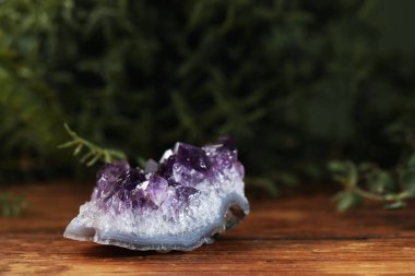 Aura. Bulanık yeşil arka planda ahşap yüzeyde güzel bir ametist, yakın plan.