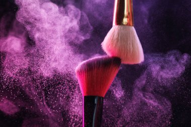 Renkli göz gölgeli makyaj fırçaları siyah arka planda neon ışıkları, yakın plan