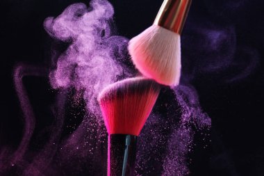 Siyah arkaplanda renkli göz gölgeli makyaj fırçaları, yakın plan