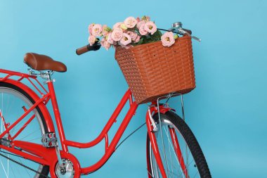Açık mavi arka planda güzel çiçeklerle dolu bir bisiklet sepeti