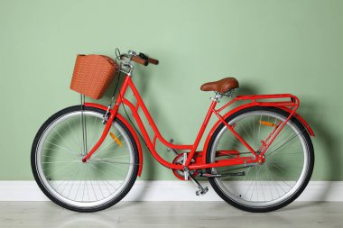 Açık yeşil duvarın yanında sepeti olan kırmızı bisiklet.