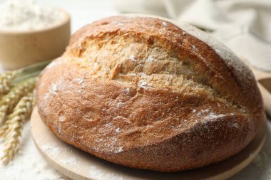 Bir somun taze ekmek, un ve çiviler masada, yakın plan.