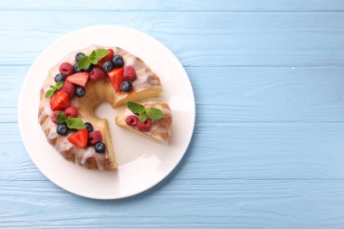 Böğürtlenli kek parçaları, açık mavi ahşap masa üzerinde şeker ve nane, üst manzara. Metin için boşluk