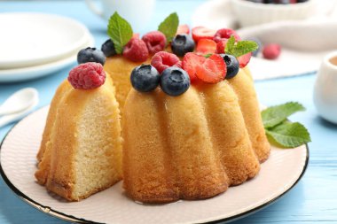 Böğürtlenli kek ve açık mavi ahşap masada nane şekeri, yakın plan.