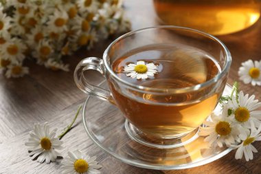 Cam bardakta romatik çay ve ahşap masada papatya çiçekleri, yakın plan.