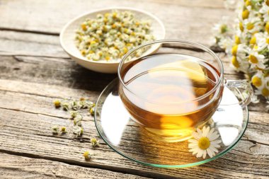 Cam bardakta romatik çay ve ahşap masada papatya çiçekleri, yakın plan.