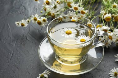 Lezzetli papatya çayı ve çiçekler siyah masada, yakın plan. Metin için boşluk