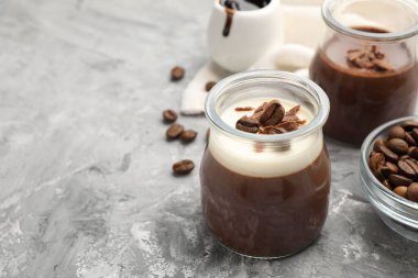 Çikolata parçalı lezzetli panna cotta ve gri desenli masada kahve çekirdekleri, yakın plan. Metin için boşluk
