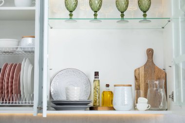 Farklı bulaşık takımları, bardaklar ve diğer mutfak gereçleri kapalı dolaplarda raflarda.