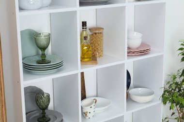 Farklı bulaşık takımları, bardaklar, baharatlar ve içeride makarna rafları.