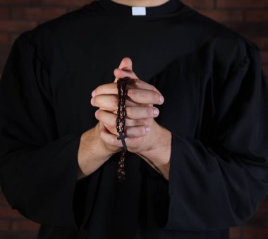 Tuğla duvarın yanında dua eden rahip, yaklaş.