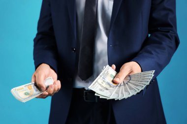 Mavi arka planda dolar banknotları olan adam, yakın plan.