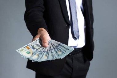 Gri arka planda dolar banknotları olan adam, yakın plan.