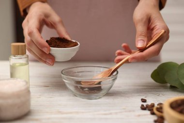 Doğal temizlik yapıyorum. Beyaz ahşap masada kahveye kahve katan kadın, yakın plan.