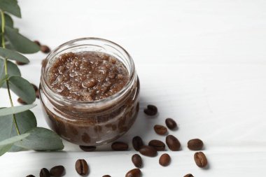 Cam kavanozda doğal vücut fırçası, kahve çekirdekleri ve okaliptüs dalı beyaz ahşap masada, yakın plan. Metin için boşluk