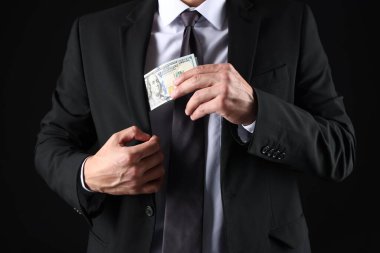 Adam siyah arka plana dolar koyuyor, yakın plan.