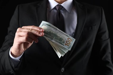 Siyah arka planda dolar banknotları olan adam, yakın plan.