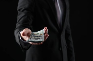 Siyah arka planda dolar banknotları olan adam, yakın plan.