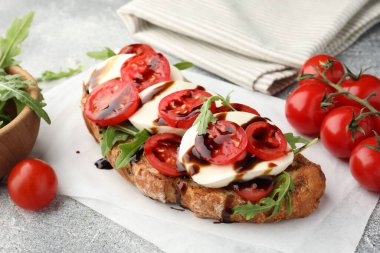 Mozarella peynirli lezzetli sandviç, balzamik sos, domates ve roka gri masada, yakın plan.