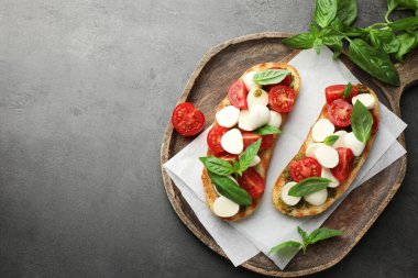 Mozarella peynirli lezzetli sandviçler, domates ve fesleğenli gri desenli masa, düz yatak. Metin için boşluk