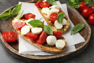 Peynirli, domatesli ve fesleğenli lezzetli sandviçler. Gri desenli masa, yakın plan.