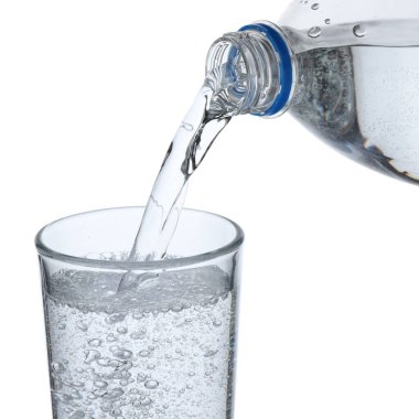 Serinletici soda suyunu beyaz arka planda şişeden cama dökerek, yakın plan