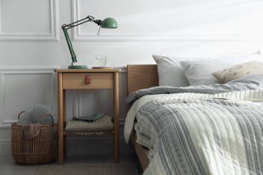 Yatak odasının yanında lamba ve bir bardak su olan komodinin yanında.