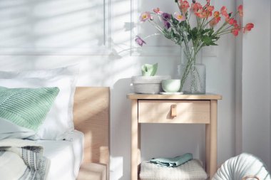 Yatağın yanında farklı dekorları olan bir komodin.