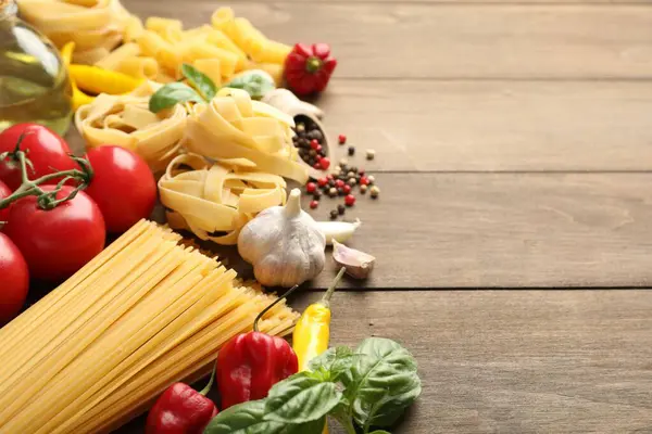 Farklı türde ham makarna ve ürünler ahşap masada, yakın plan. Metin için boşluk