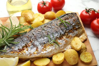 Beyaz mermer masada baharatlı ve sebzeli kızarmış uskumru, yakın plan. Ev yapımı deniz ürünleri yemeği.