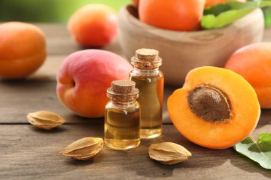 Şişelerdeki, tohumlardaki ve olgun kayısılardaki yağlar ahşap masada, yakın plan.