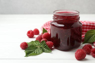 Lezzetli reçel, taze ahududu ve beyaz ahşap masa yaprakları, yakın plan. Metin için boşluk