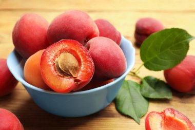 Birçok taze kayısı ve yeşil yapraklar ahşap masada, yakın plan