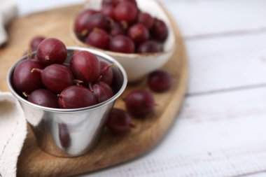 Beyaz ahşap masada kasede olgun kırmızı bektaşi üzümleri, yakın plan. Metin için boşluk