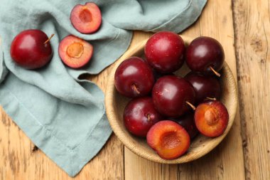 Olgun kiraz erikleri, kase ve kumaş ahşap masada, düz uzanmış.
